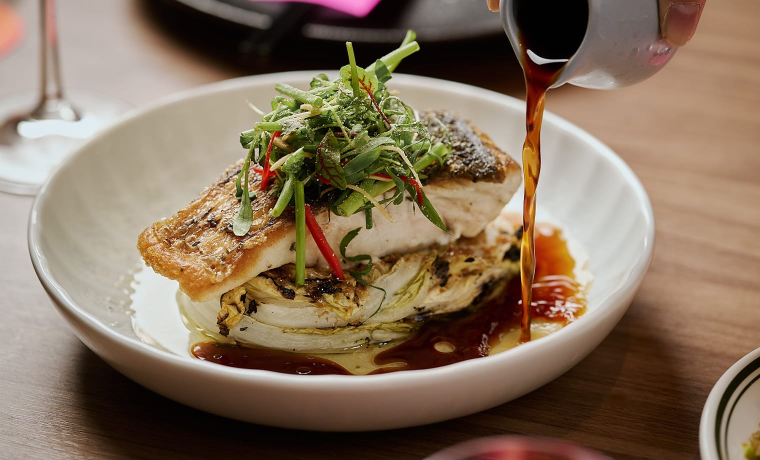 Sauce poured over crisp-skinned fish on charred cabbage at Salted Egg Melbourne